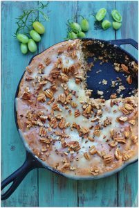 Green Tomato Skillet Cake. Spice cake with green tomatoes, pecans and raisins topped with a warm butter icing and toasted pecans.