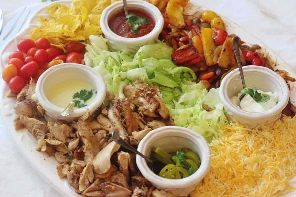 Chicken Fajita Salad. Marinated and roasted chicken thighs with seasoned peppers and onions served on a bed of lettuce with traditional fajita toppings.