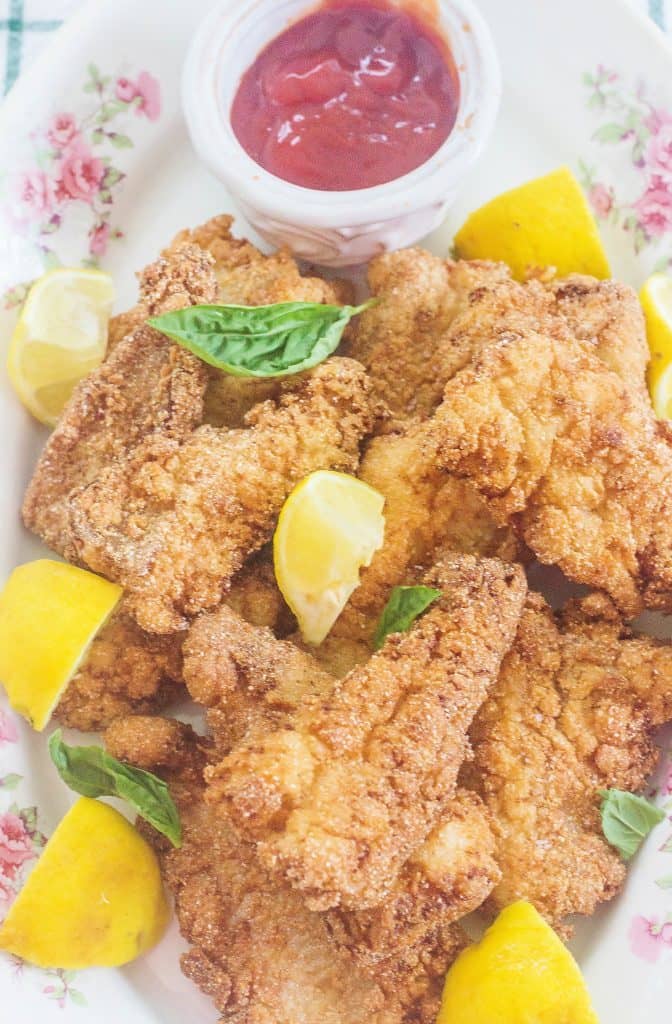 Southern Fried Catfish on platter with lemons and dipping sauce.
