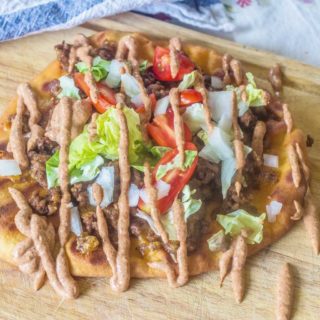 Grilled Flatbread Taco Pizza with Creamy Taco Sauce. Made with pre-packaged naan bread, taco seasoned ground beef and your favorite taco toppings. Topped with an easy and creamy homemade taco sauce.